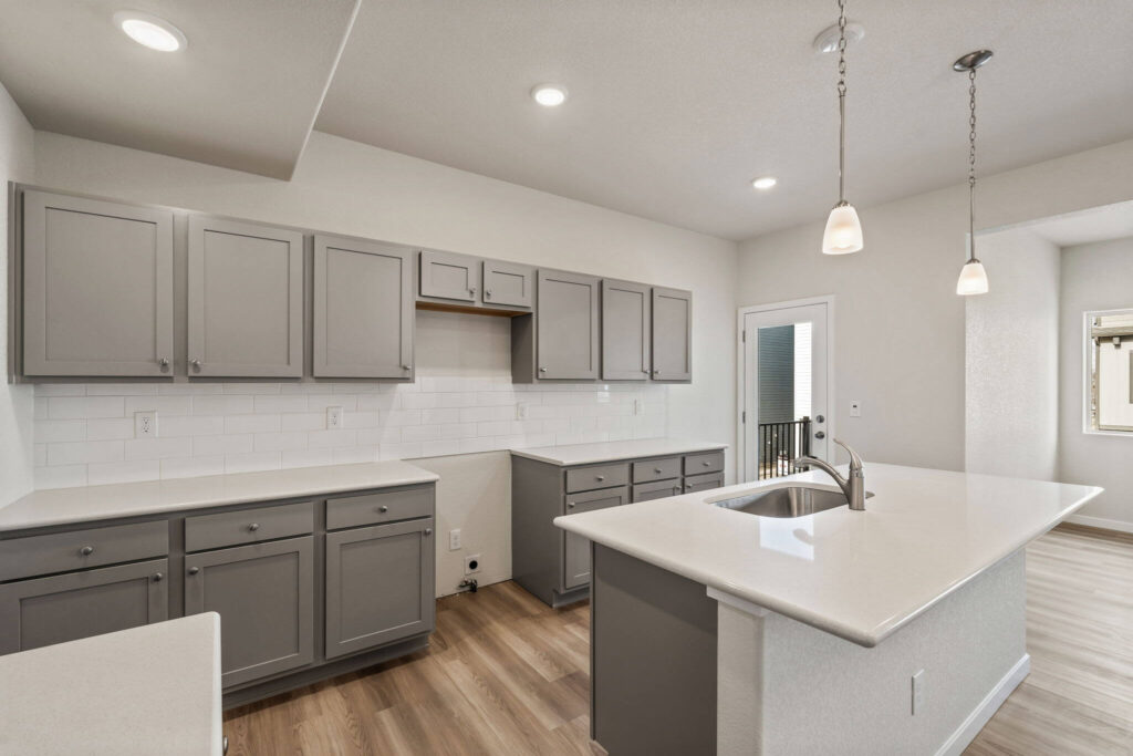 Kitchen from a different angle showing cabinetry, countertop space and pendant lights.