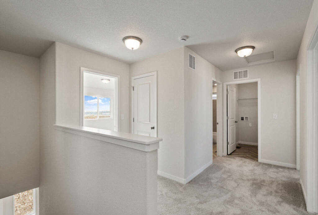 Upper hallway landing with carpeted floor, doors to rooms, and overhead ceiling lights.