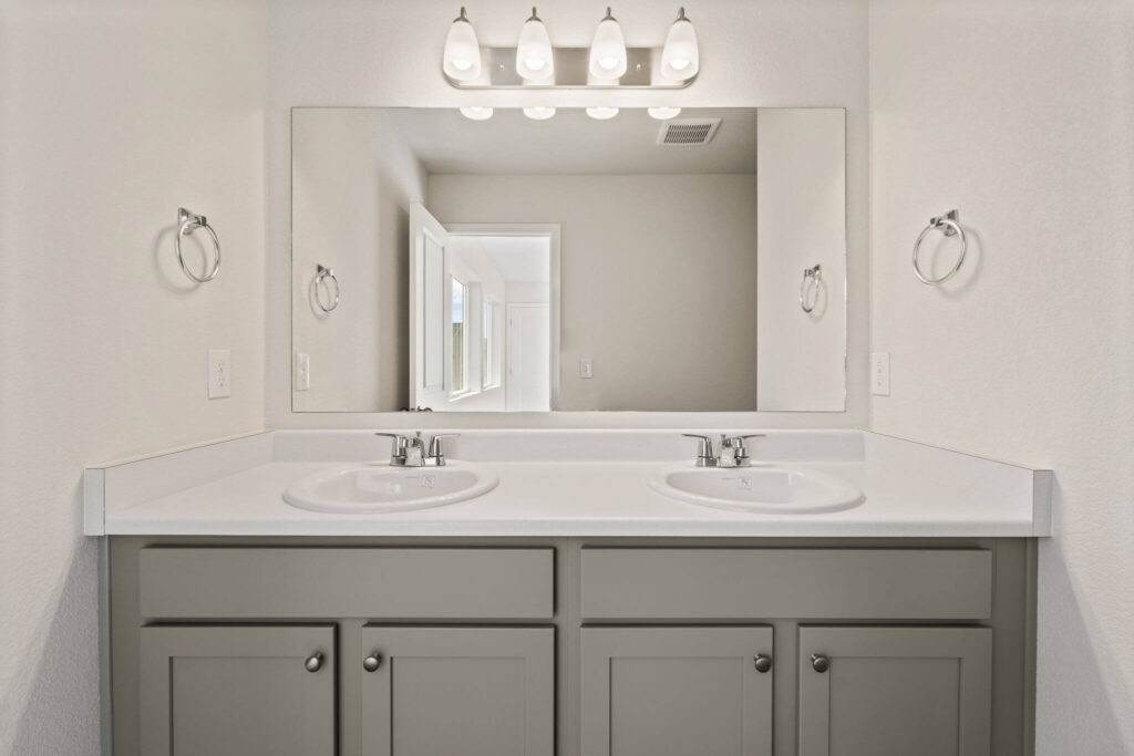 Double-sink bathroom vanity with large mirror and overhead vanity light fixtures.