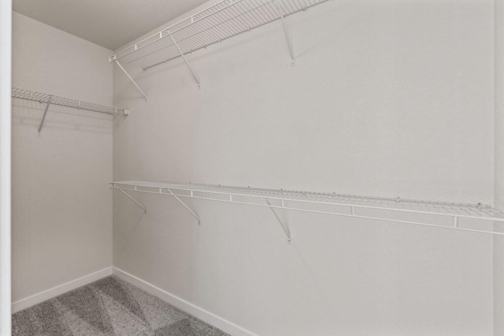 Walk-in closet with wire shelving and carpeted floor.
