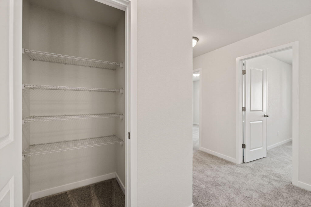 Hallway view showing an open closet with wire shelves and adjacent room doorways.