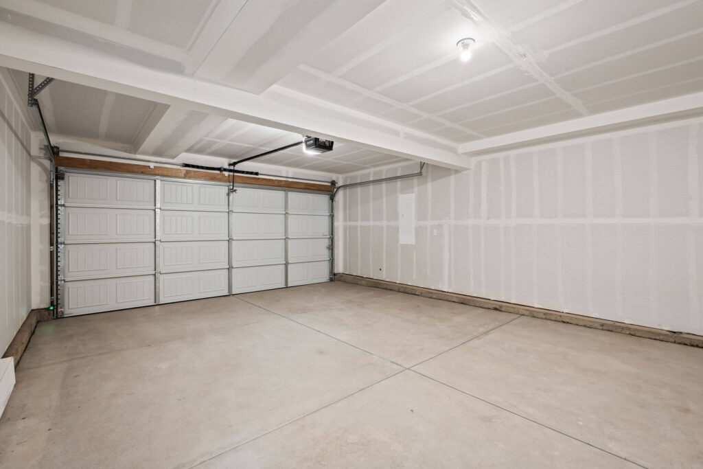 Empty two-car garage interior with concrete floor and closed sectional garage door.