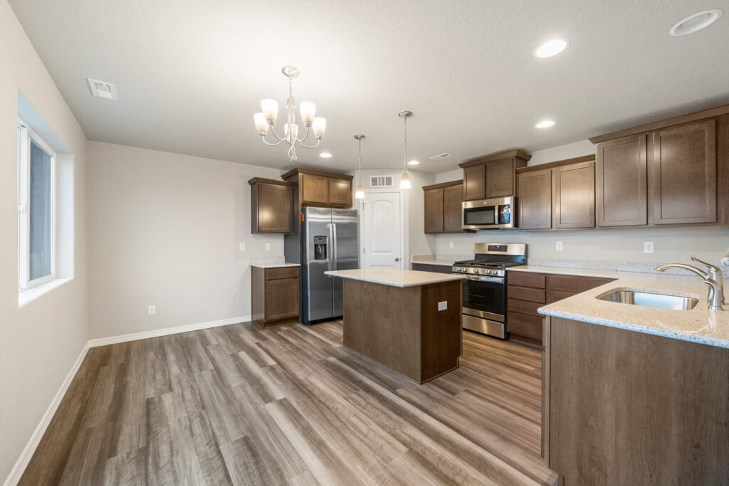 Kitchen and dining nook with center island, chandelier and stainless steel refrigerator.