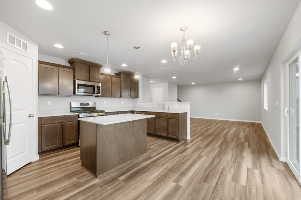 Kitchen and open living area from island perspective with sliding door to outside.