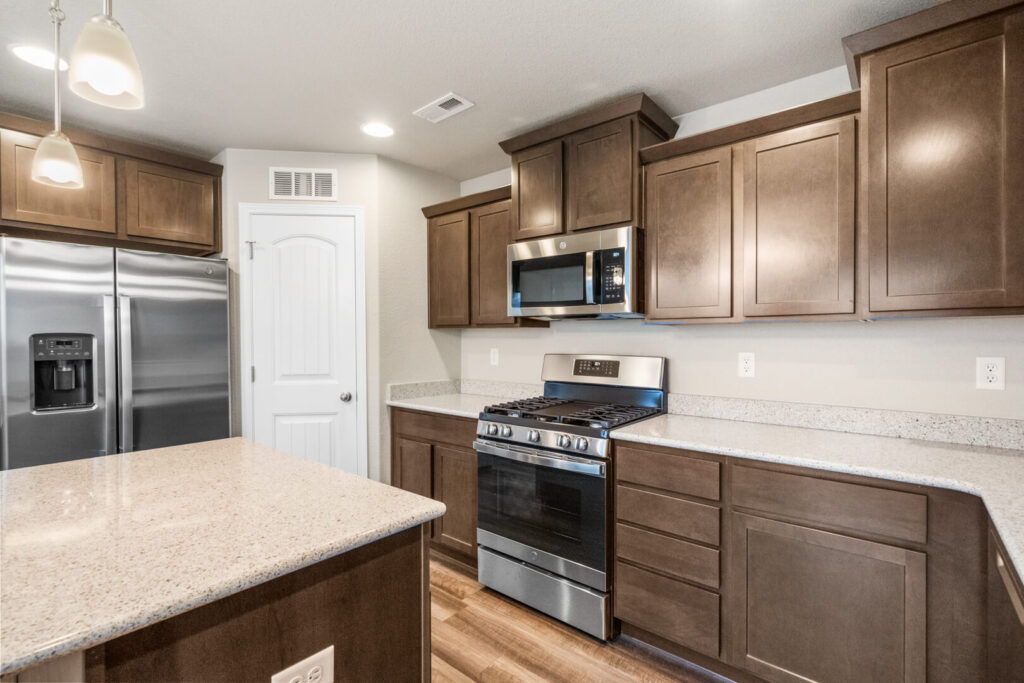 Close-up of kitchen appliances and cabinetry showing gas range, microwave, and refrigerator.