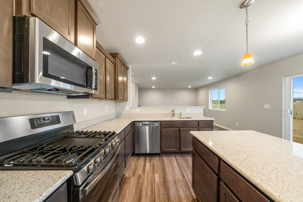 Modern kitchen with stainless steel range, microwave, dishwasher, and quartz-look counters.
