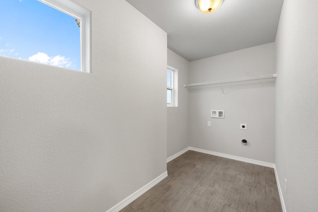 Narrow utility or laundry room with two small windows, shelving, and washer/dryer hookups.
