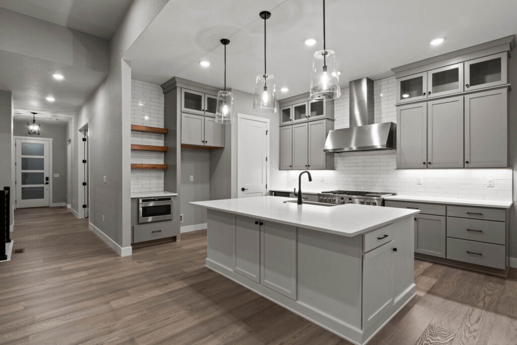 Angle view of kitchen island, cabinets, stainless hood, open shelving, and hallway entrance.