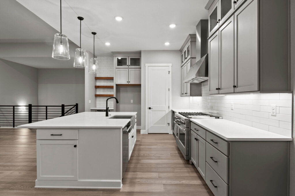 Kitchen island and long countertop run with stove, hood, and floating wood shelves.