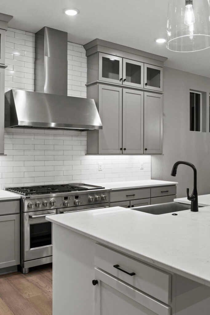 Modern kitchen with stainless steel range, white island countertop, and black faucet.