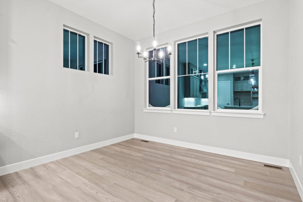 Empty dining or breakfast nook with three windows and overhead chandelier.