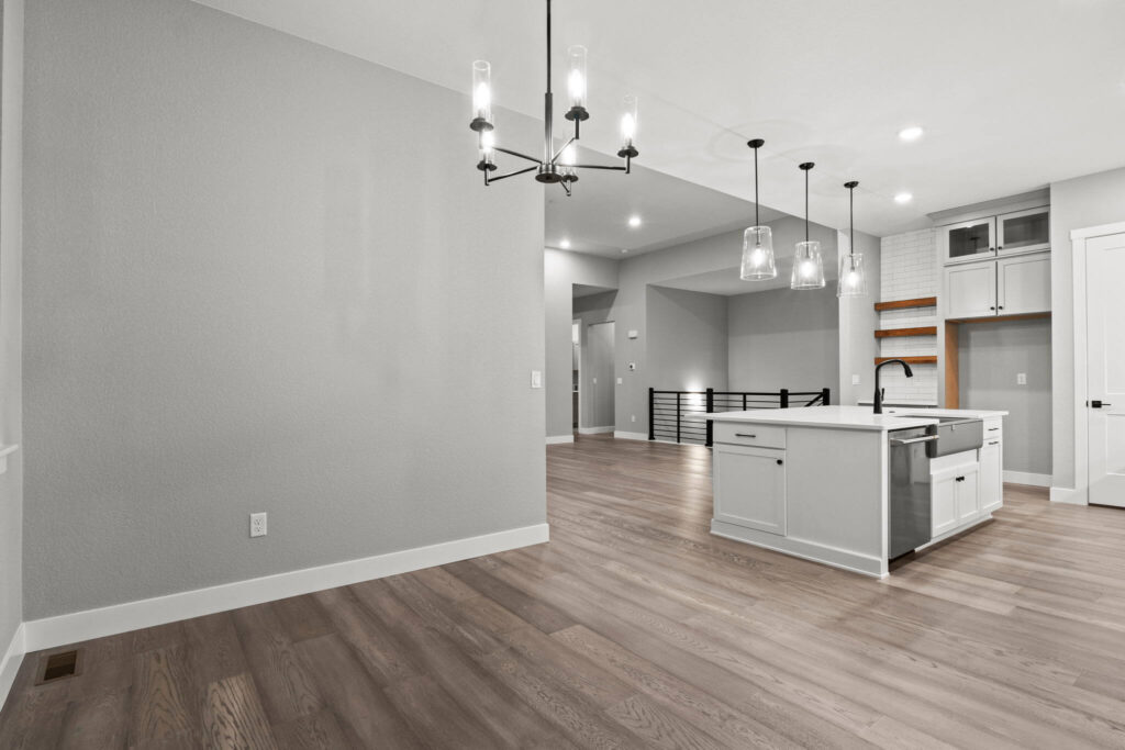 Open-plan kitchen and living area with island, pendant lights, and wood-look floors.