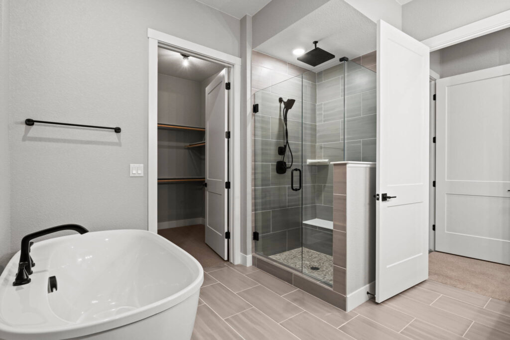 Bathroom with freestanding tub, glass-enclosed shower, and a walk-in closet door.