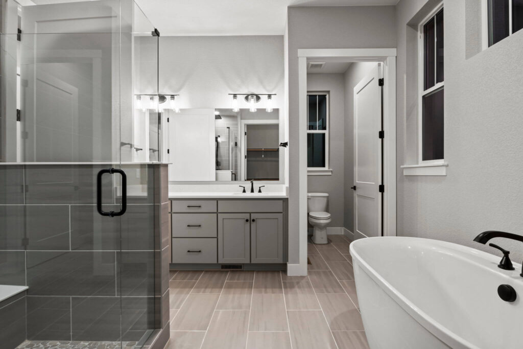 Modern bathroom with freestanding tub, glass shower, and double-sink vanity in neutral tones.