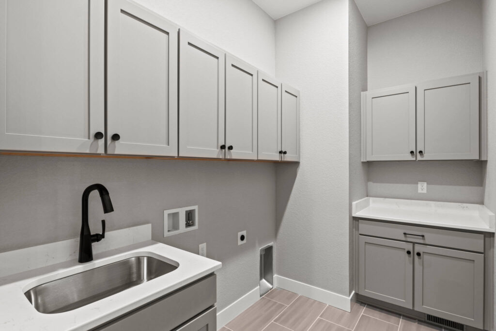 Laundry or utility room with sink, countertop, upper cabinets, and washer/dryer hookups.