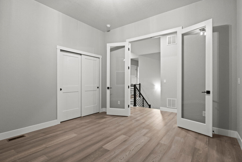 Interior room with double glass doors opening to a hallway and sliding closet doors on one wall.