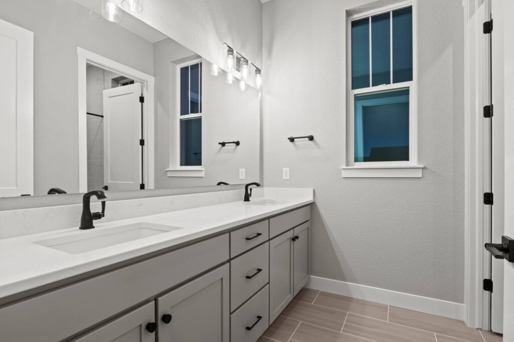 Modern bathroom vanity with dual sinks, large mirror, and matte black fixtures.