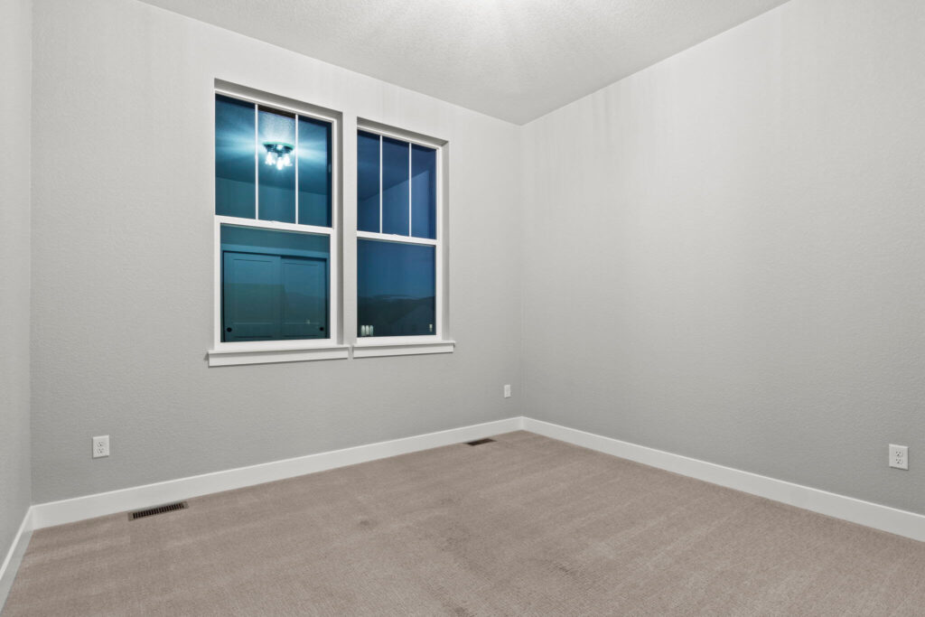 Empty room with two double-hung windows, neutral walls, and carpeted floor.