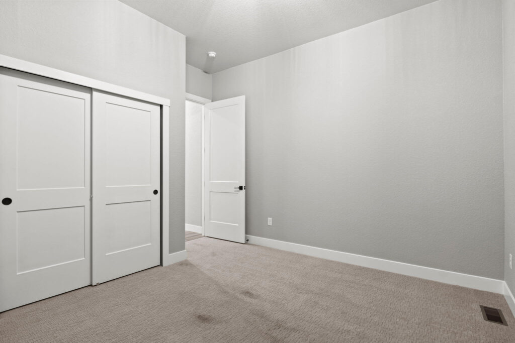 Carpeted room showing sliding closet doors and an open entry door.