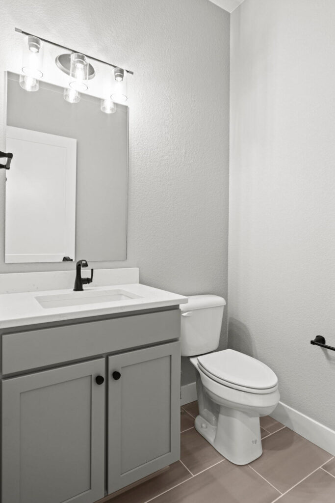 Small bathroom with single sink vanity, mirror, and a toilet beside the cabinet.