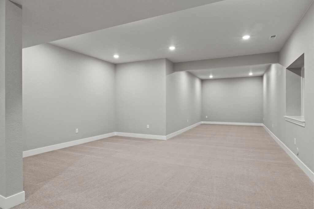 Long, empty carpeted basement corridor with recessed lighting and neutral painted walls.