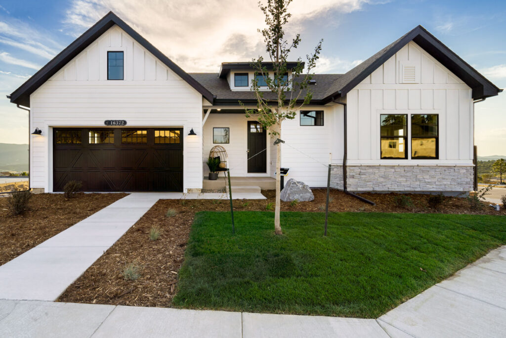 Single-story white house with dark garage door, front porch, and small newly sodded lawn.