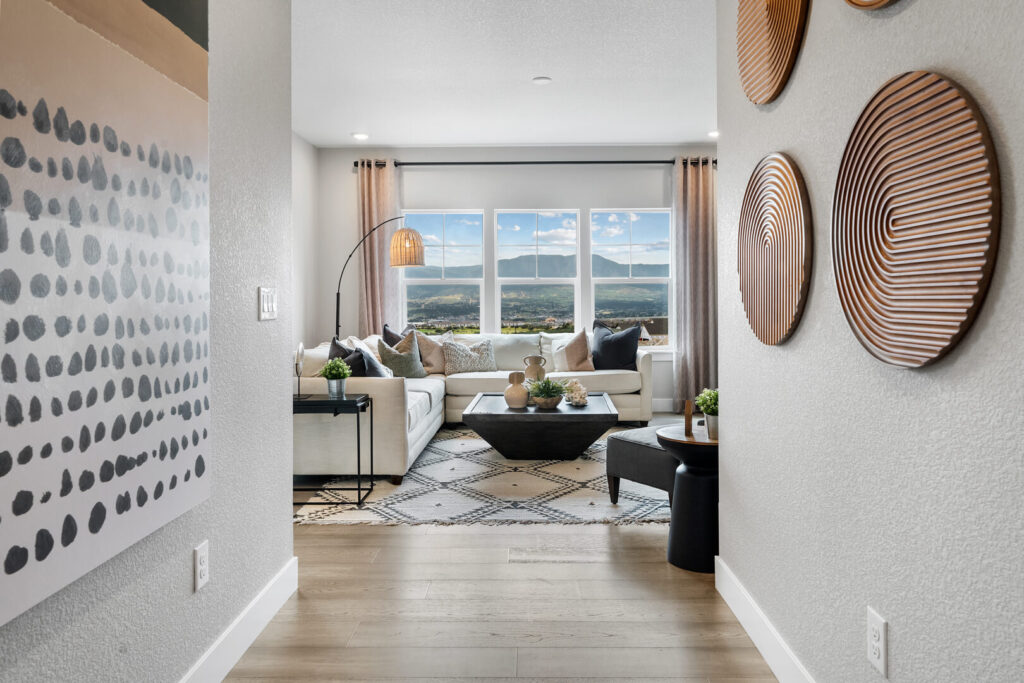Entry view into a bright living room with large window and decorative wall art in foreground.