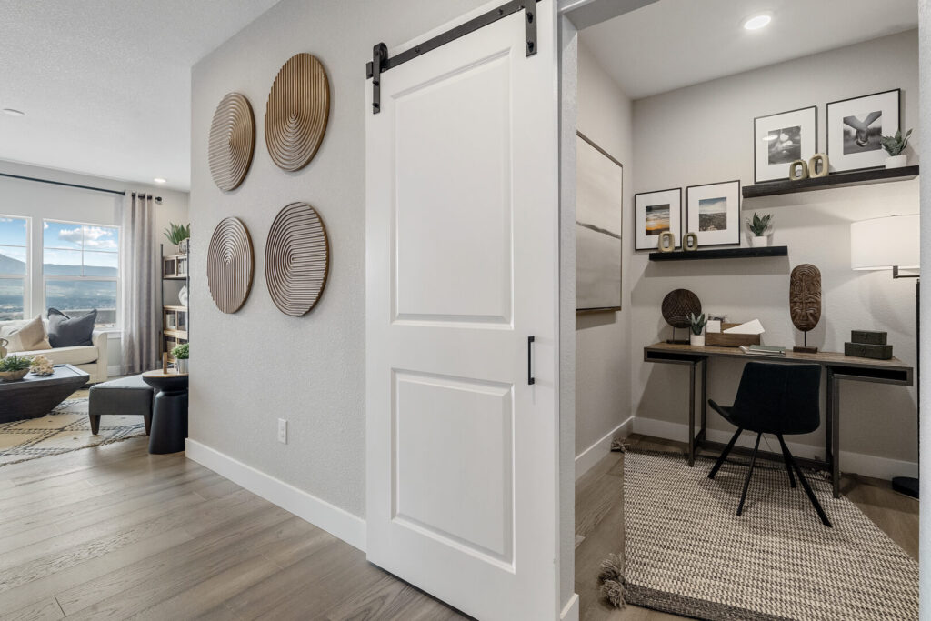 Hallway with sliding barn door leading to a small furnished office nook and decorative wall discs.