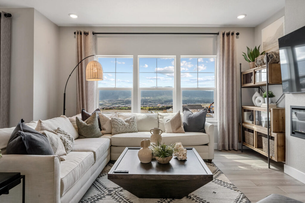 Bright living room with large windows, sectional sofa, coffee table, and floor lamp.