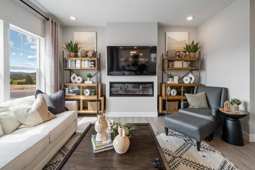 Cozy sitting area with wall-mounted TV above a linear fireplace and shelving on both sides.