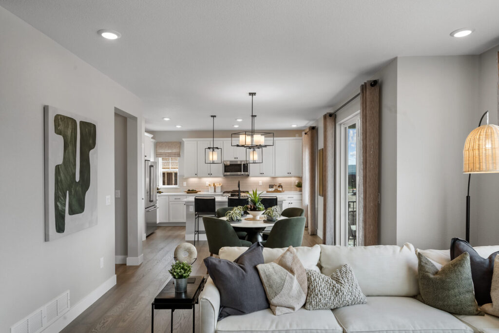 Open-plan living area looking toward a kitchen with dining table and pendant lights.