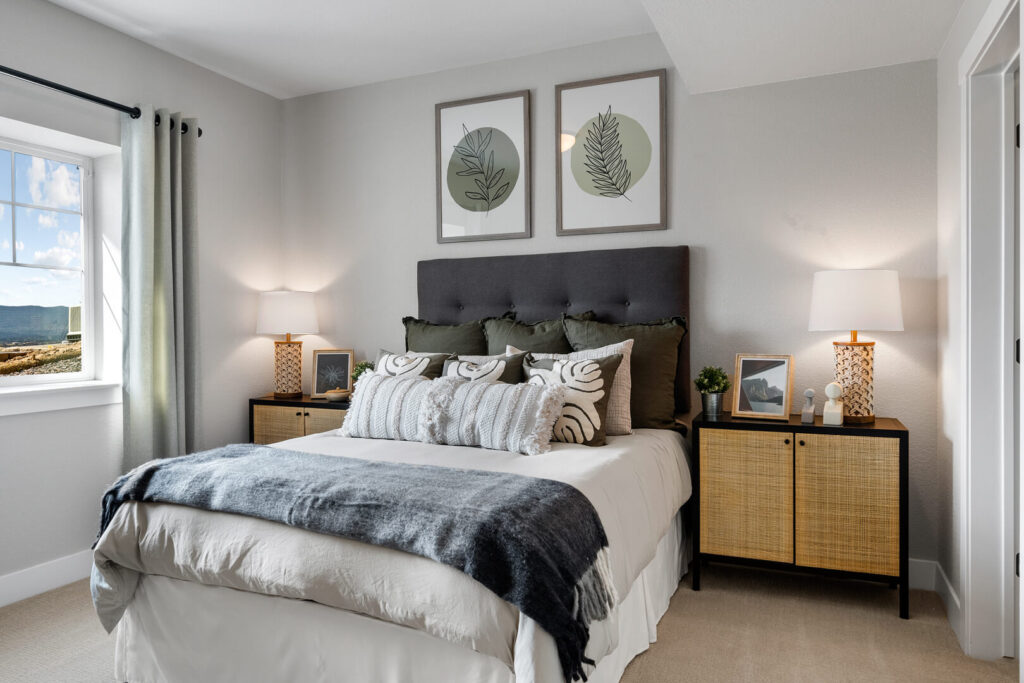 Bedroom featuring a bed with dark upholstered headboard, bedside tables, and botanical wall art.