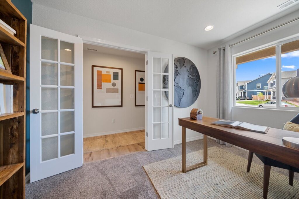 Home office seen from inside showing French doors, desk, window and wall-mounted world map.