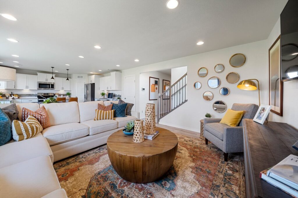 Living room view from the coffee table showing sofa, accent chair, and wall of circular mirrors.