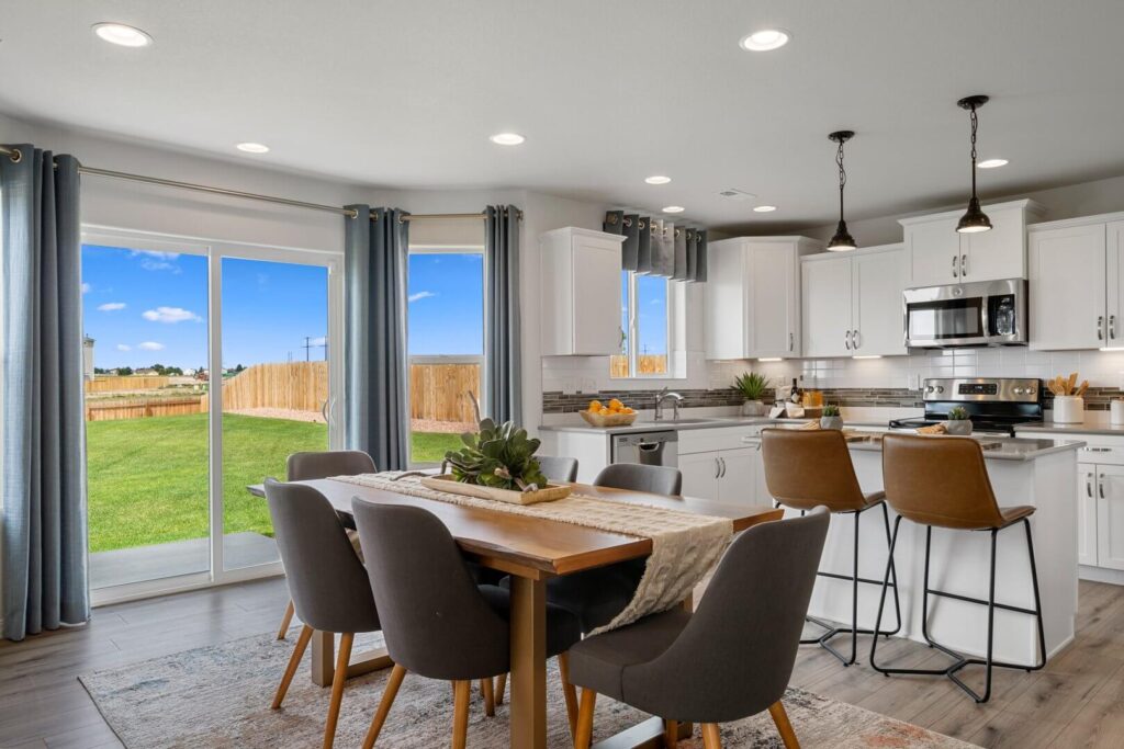 Dining area by sliding glass doors with a table, six chairs, and a kitchen island with bar stools.
