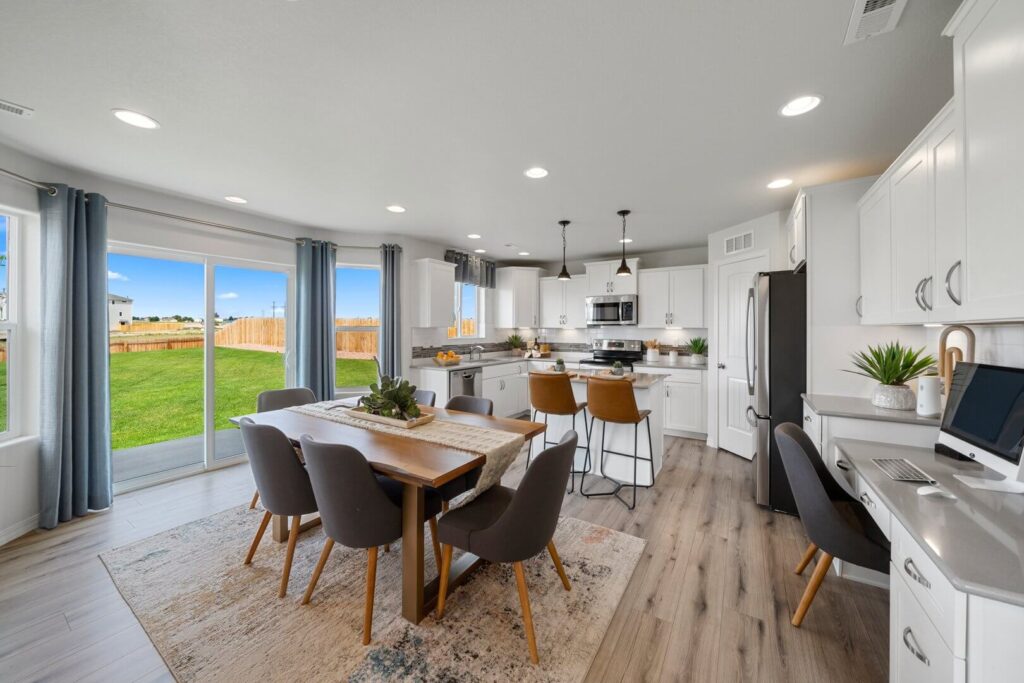 Open-plan dining area and kitchen with sliding glass doors and wood-look flooring.