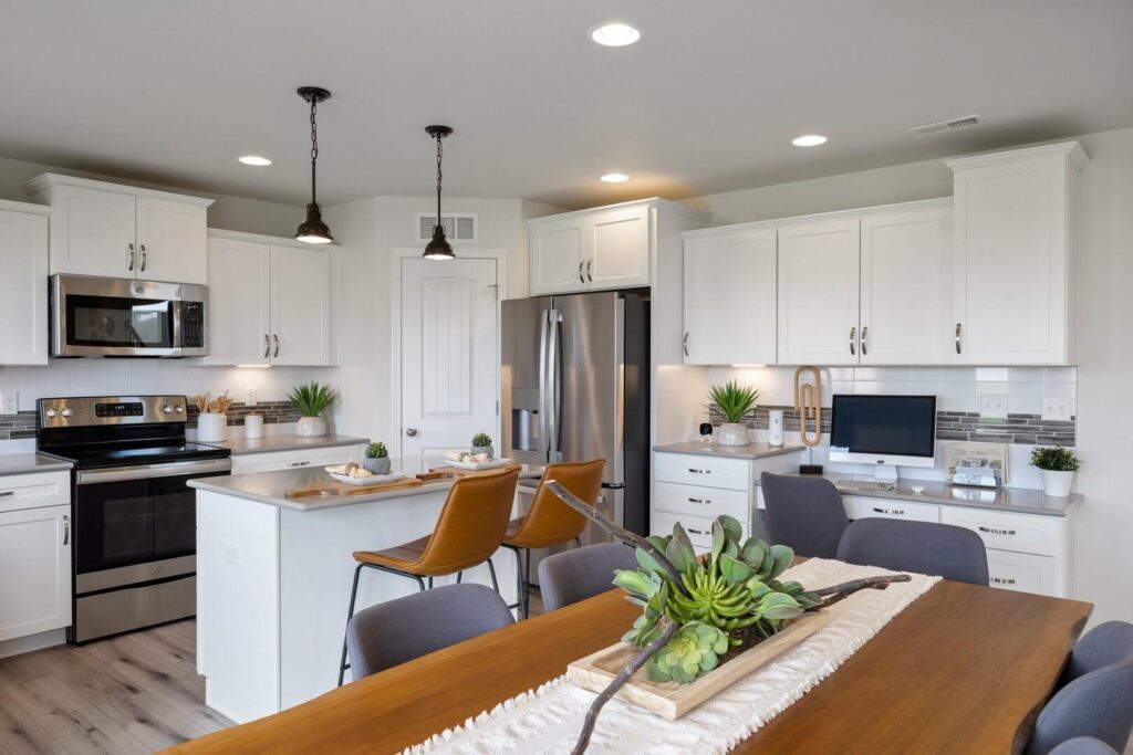 View from dining table toward kitchen island with leather barstools and stainless appliances.