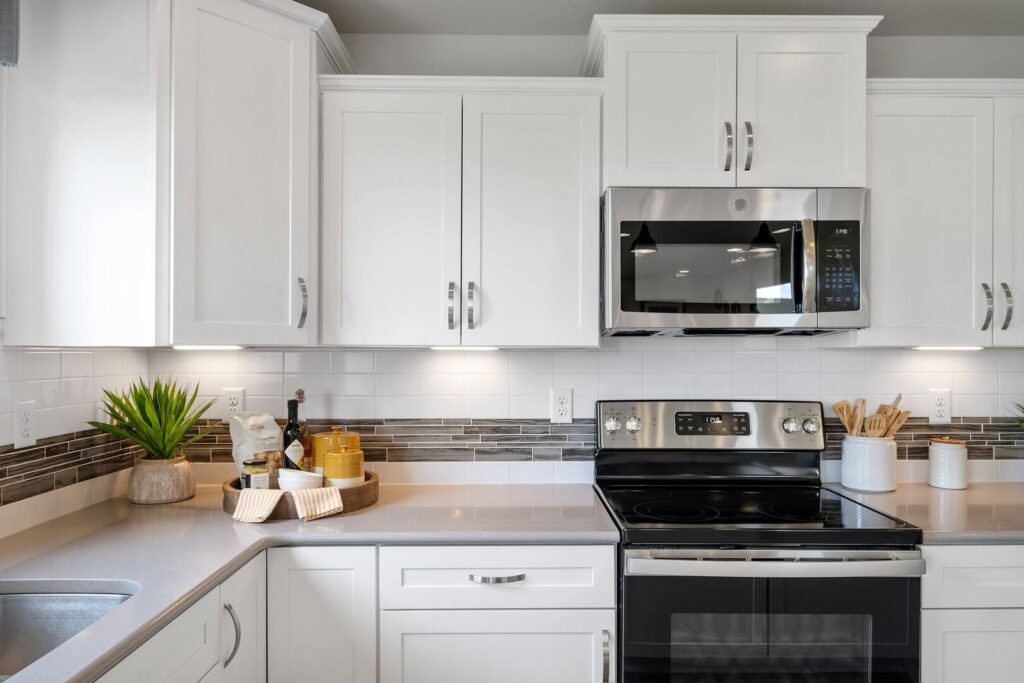 Close-up of stovetop and surrounding white cabinets with stainless microwave above.