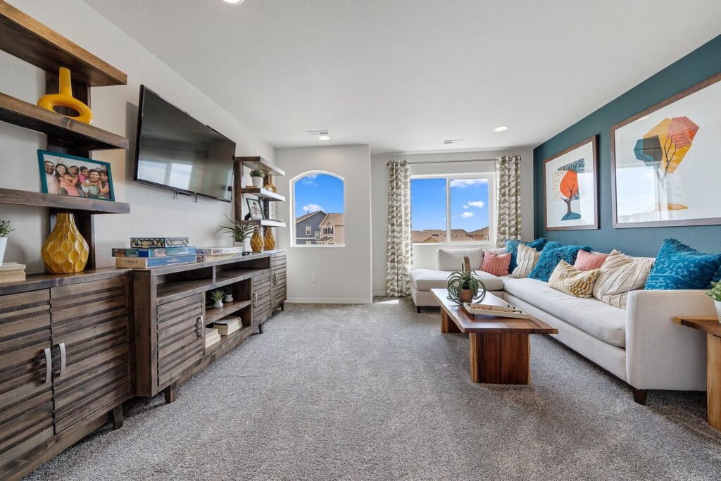 Casual upstairs family room with a wall-mounted TV, wooden media cabinets, and a sofa.