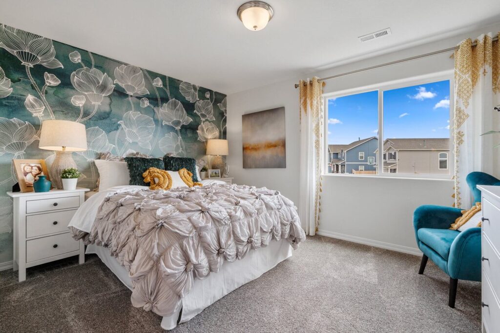Staged bedroom with floral-accent wallpaper, bed, nightstands and a window with neighborhood view.