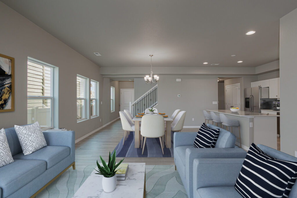 Open-concept living and dining area with blue sofas, dining table, and multiple windows.