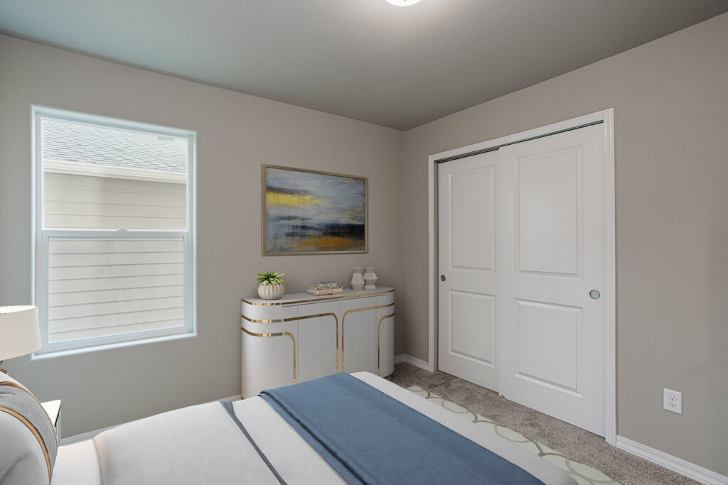Small bedroom corner with bed, decorative console, closet with sliding doors and window.