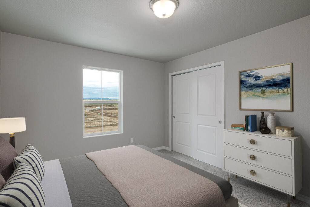 Simple bedroom with bed, dresser, closet and single window looking out to a construction area.