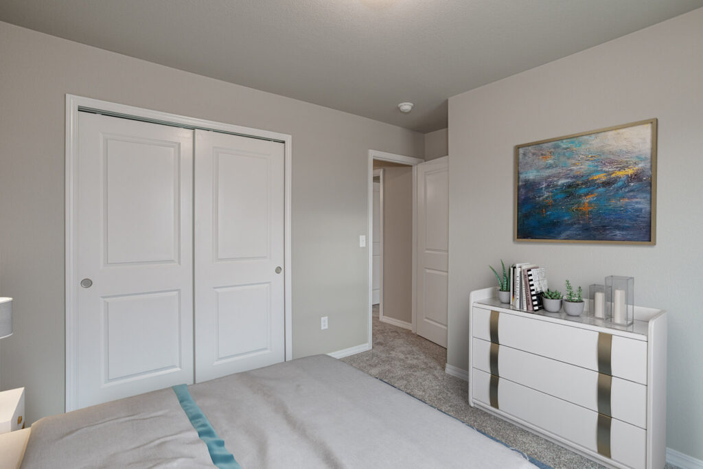 Bedroom interior looking toward sliding closet doors and a white dresser with decorative items.