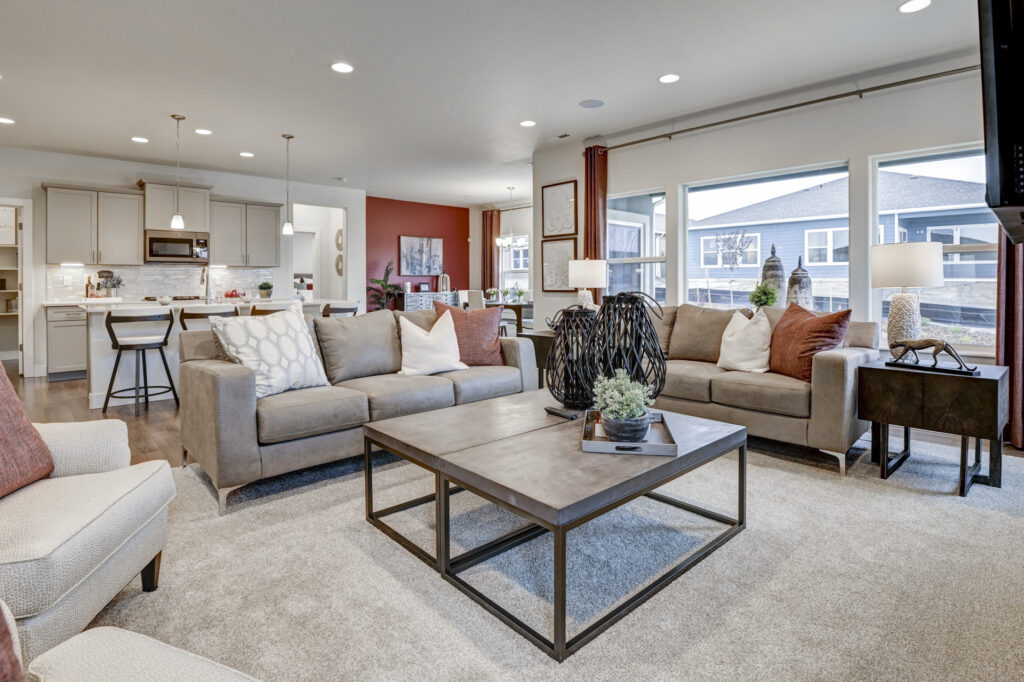 Bright open living room with two beige sofas, large coffee table, and wide windows.