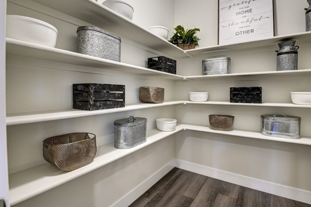 Pantry shelves lined with metal and ceramic storage containers and decorative baskets.