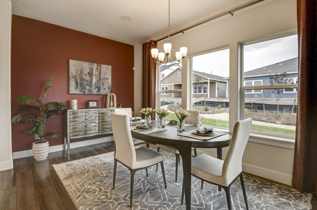 Dining corner with four chairs, a decorative sideboard, red accent wall, and large windows.