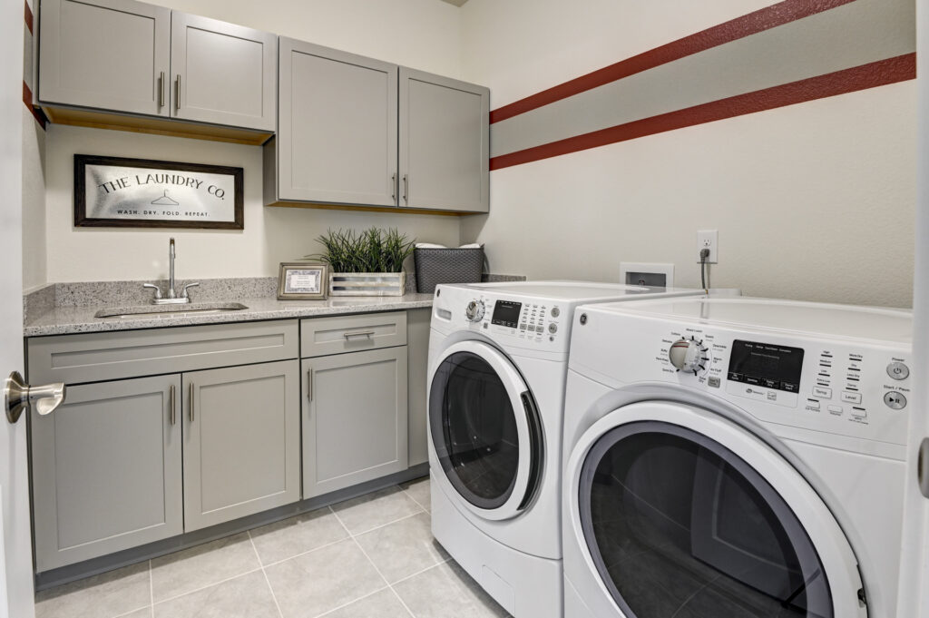 Laundry room with front-loading washer and dryer, countertop, and upper cabinets.