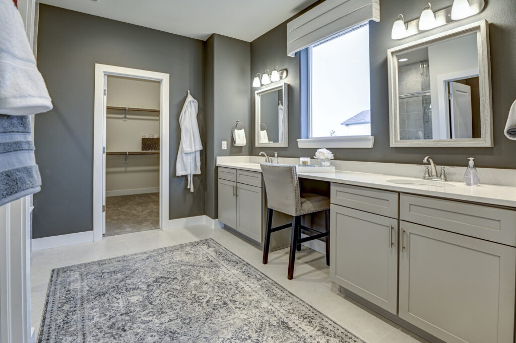 Double-sink bathroom vanity with makeup station, mirror, and doorway to walk-in closet.