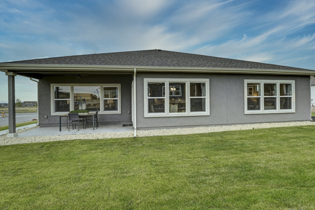 Rear elevation of a single-story home with covered patio, sliding door and lawn.